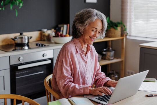 Woman working from home using laptop in kitchen