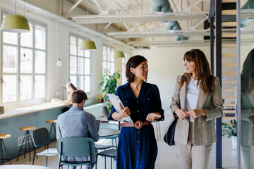 Businesswomen having a conversation while walking in office