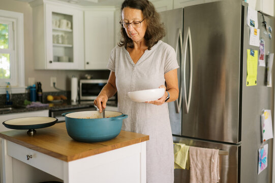 woman putting leftover food into bowl to reheat for lunch