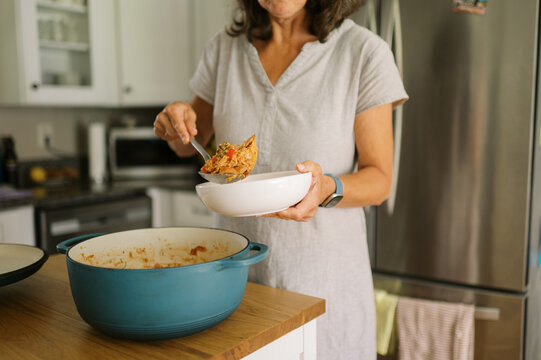 woman putting leftover food into bowl to reheat for lunch