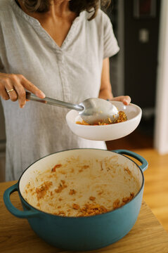 woman putting leftover food into bowl to reheat for lunch