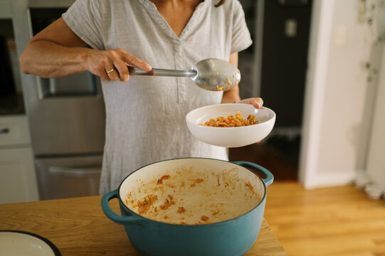 woman putting leftover food into bowl to reheat for lunch