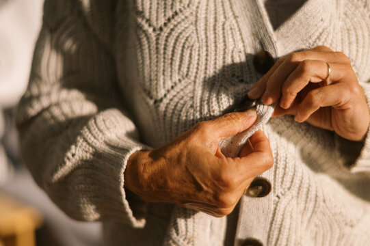 woman getting dressed the morning and buttoning cardigan