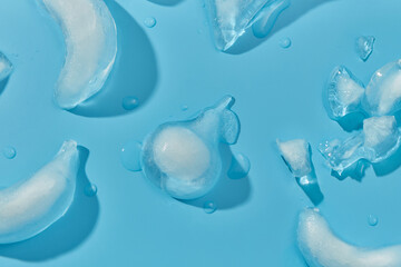 Fruits figures made of ice placed randomly on blue studio surface