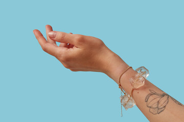 Cropped hand of woman showing two golden bracelets with ice cubes