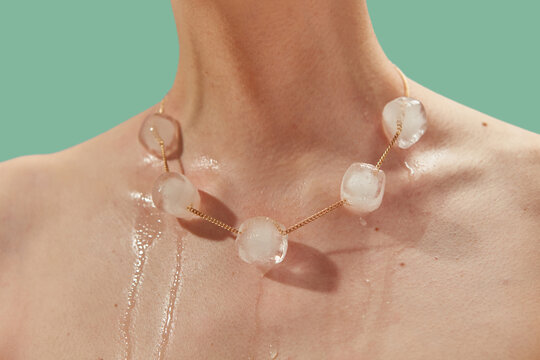 Ice balls pierced with gold chain melting under influence of skin