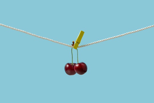 Red cherries with pegs attached to clothes line in studio