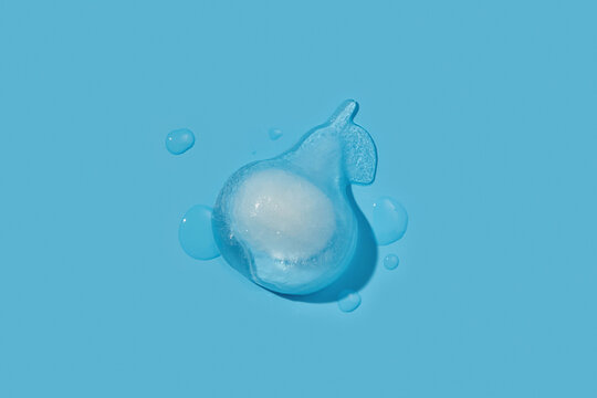 Water drop creating figure in pear shape on blue studio background
