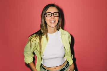 Cheerful woman in glasses smiling against a vibrant pink background