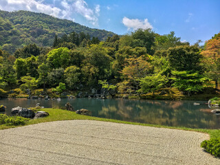 Serene raked dry garden in foreground and lake and forest in background in Japan