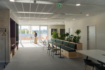 Woman Standing In A Bright Office With Large Windows