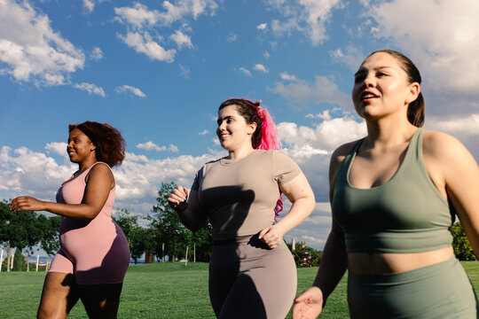 Three curvy female friends train their fitness by running outdoors