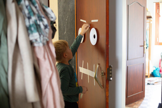 boy decorates the door before halloween holidays