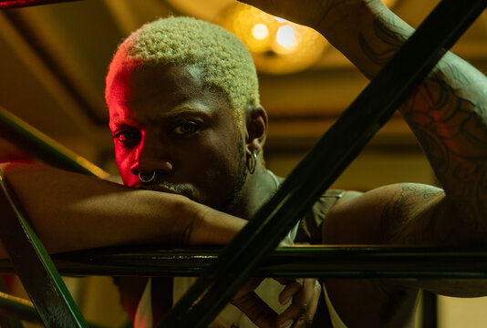 Cool Man With Blond Hair Leaning On Railings At Night.