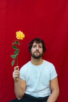 Man Holding Yellow Rose in Front of Red Background