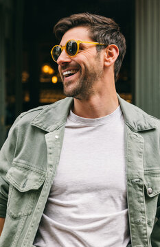 Man laughing wearing yellow sunglasses and casual outfit outdoors