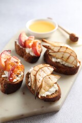 Delicious bruschettas with ricotta cheese and honey on light grey table, closeup