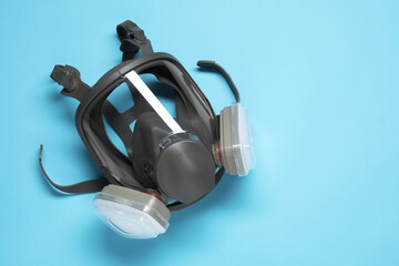 One full face respirator on light blue background, top view. Space for text