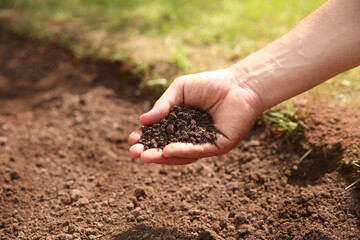 Woman holding pile of soil outdoors, closeup. Space for text