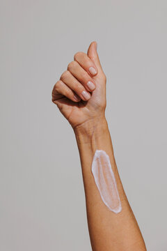 Woman applying moisturizer cream on her arm for skincare