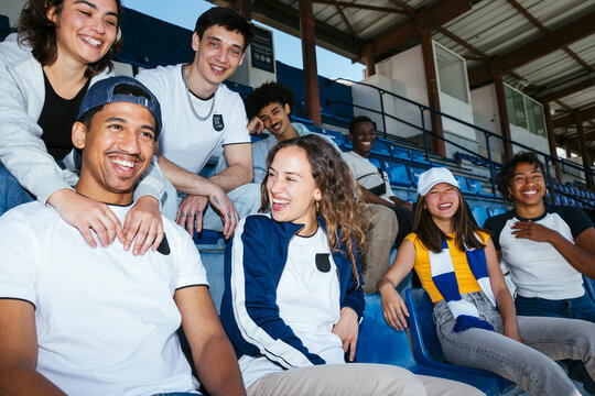 Diverse young people having fun sitting at bleachers