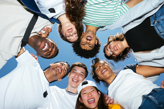 Group of diverse young adults forming circle together