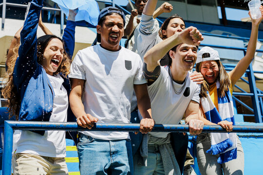 Group of friends cheering at stadium having fun together