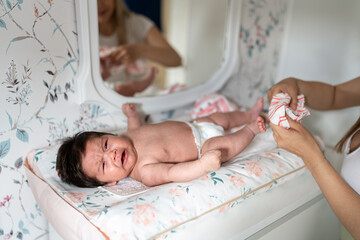 Venezuelan newborn baby boy crying while being changed by his mother