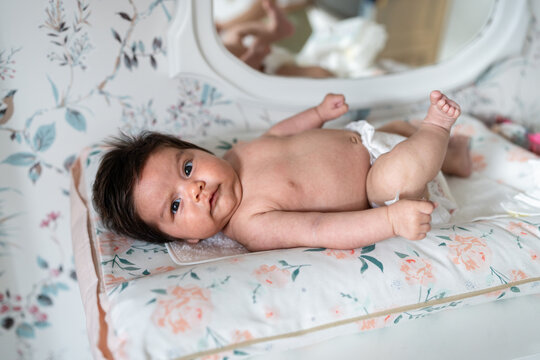 Hispanic baby lying on back on changing mat wearing diaper