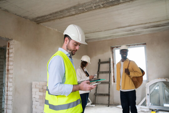 Architect Using Phone During Construction Site Visit With Colleagues