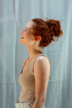 Red-hair woman with bun in profile smiling in studio
