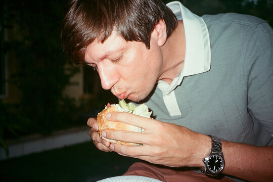  A man eating a burger in the evening