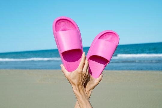 man on the beach raise his pink sandals
