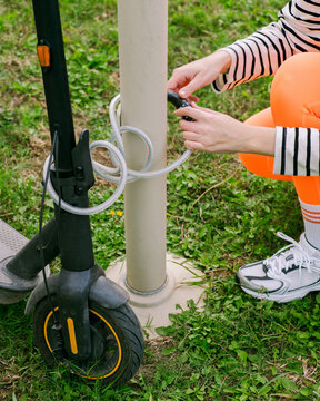 A woman straps an e-scooter to a pole