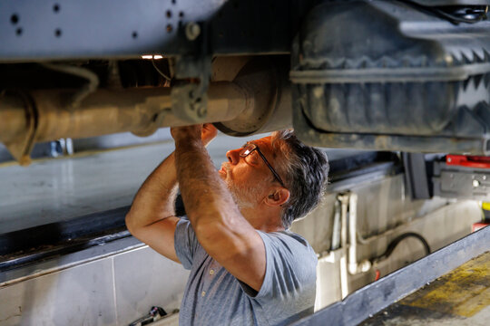 Technician wearing eyeglasses examing car parts in auto repair shop