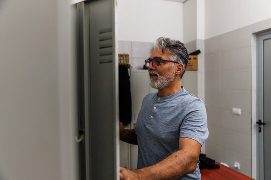 Smiling worker looking into locker before working at industry