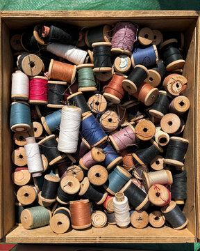 disorder in box with many spools of thread
