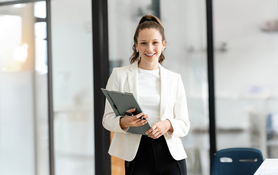 Smiling mature professional business woman manager, older happy female executive or lady entrepreneur holding fle folder standing in office at work, looking at camera.