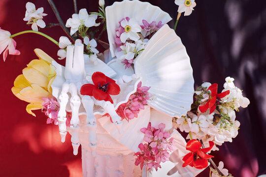Skeleton Hand Holding Flowers in White Vase