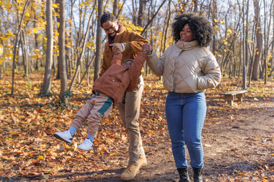 Playful parents with toddler son in autumn park