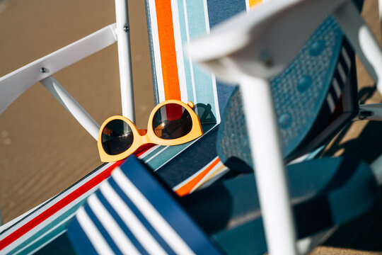 sunglasses and sandal on a striped folding chair on the beach