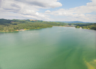 A large river with hilly green banks. Blue cloudy sky. Beautiful landscape. Rest, solitude, relaxation, romance, ecology.