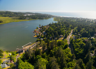 Fototapeta premium A small town among a green forest on the banks of a river. Aerial view. Recreation, fishing, bathing, swimming.