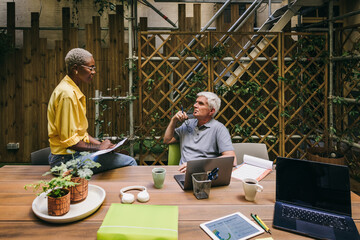 Outdoor meeting in urban garden with laptops and coffee