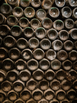 Dusty wine bottles stacked in a cellar showcasing vintage aging