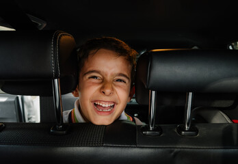 Laughing child behind car seat, enjoying a road trip moment
