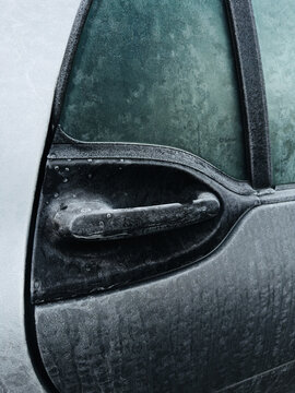 Frost-covered vehicle door and handle in cold winter weather