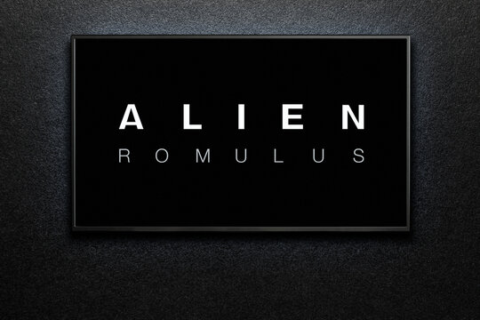 Alien Romulus trailer or movie on TV screen. TV on black textured wall.