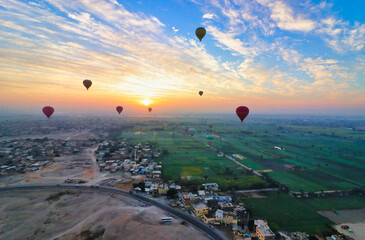 Hot Air balloons rise over the outskirts of Luxor with agricultural fields and archaeological sites offering tourists grand vistas over the town and the desert near Luxor,Egypt 