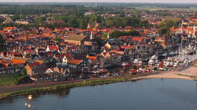 Charming waterfront and historic architecture of Urk from above. Vibrant red rooftops, a scenic harbor, and lush greenery create an idyllic European town setting